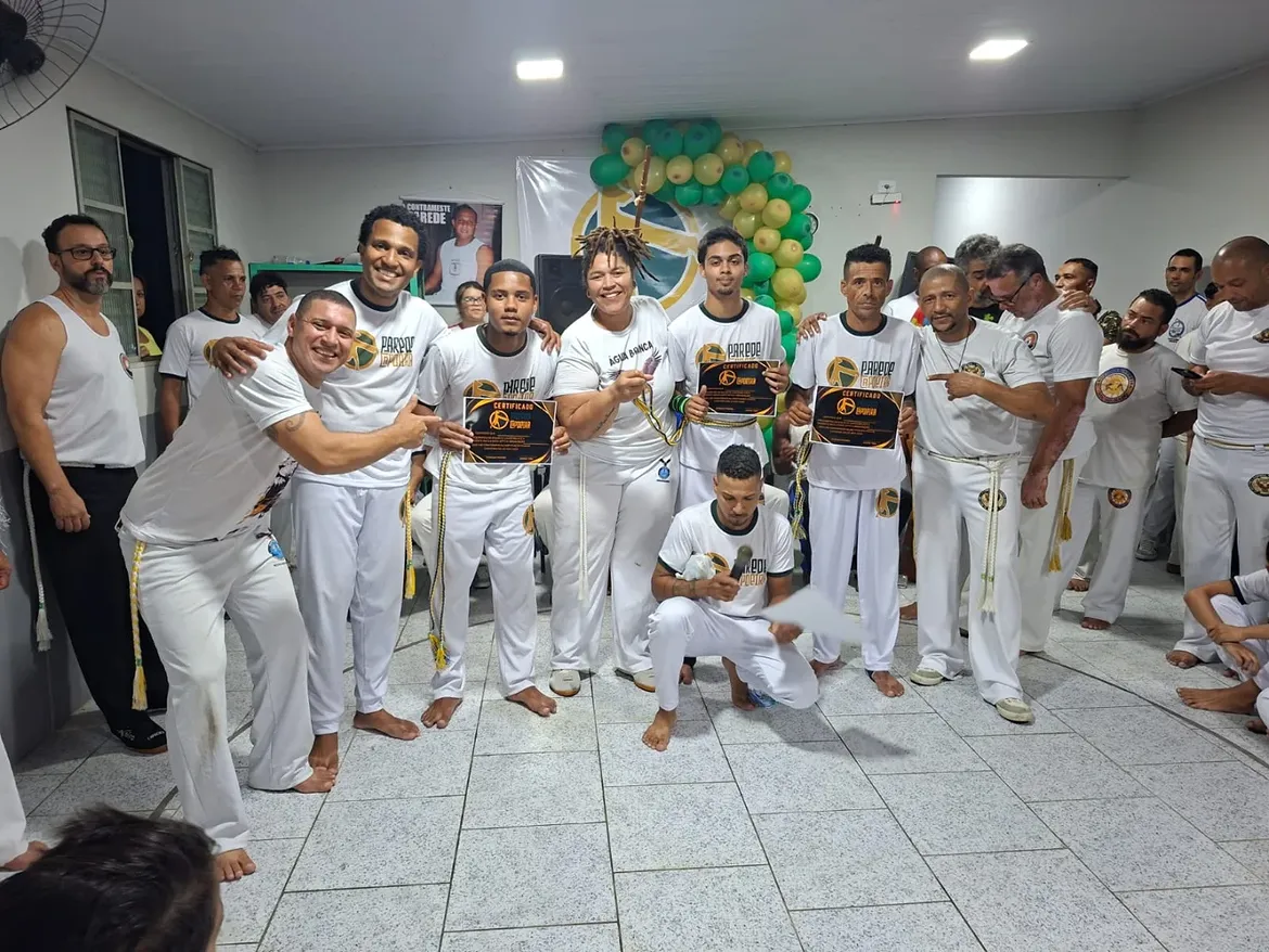 Alunos exibindo certificados de graduação com os professores