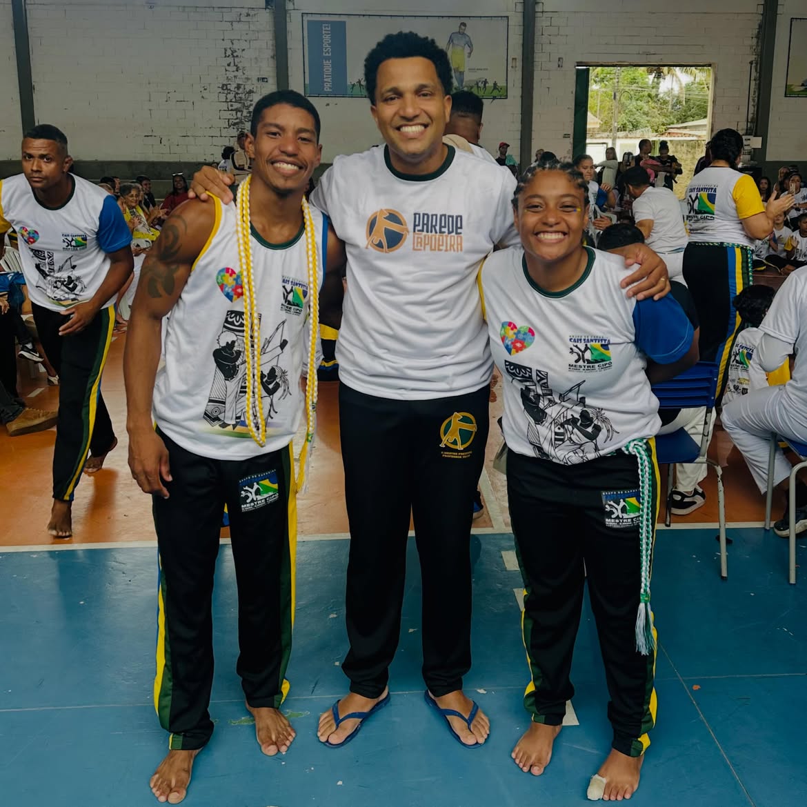 Professor do Parede Capoeira ao lado de dois alunos graduados durante encontro